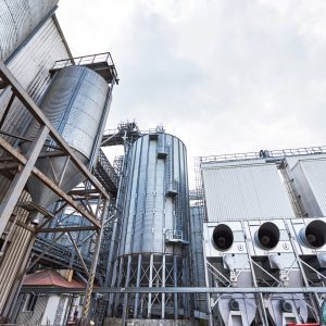 Agricultural Silos. Building Exterior. Storage and drying of grains, wheat, corn, soy, sunflower against the blue sky with white clouds.